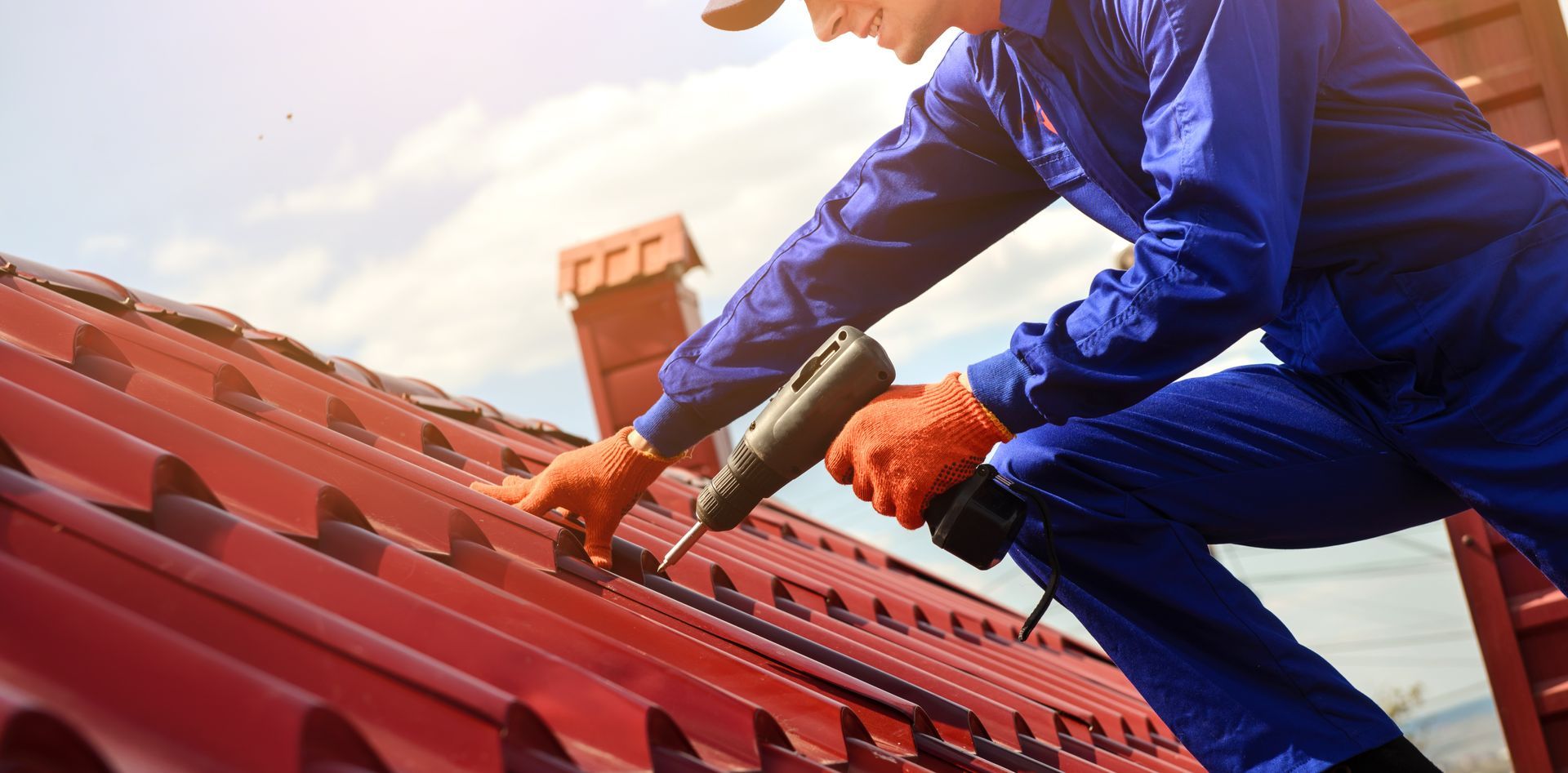 Close-up of roofing contractor in blue overalls on job site during sunny day.