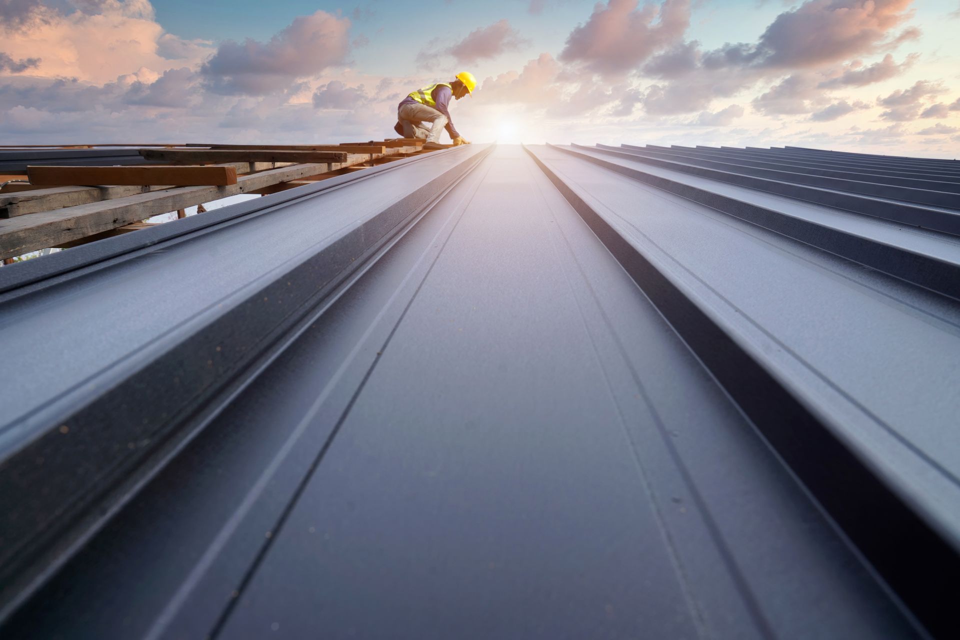 Commercial roofing contractors securing metal sheets with drills and roofing tools.