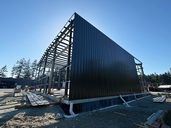Metal building under construction with one side of wall panels added