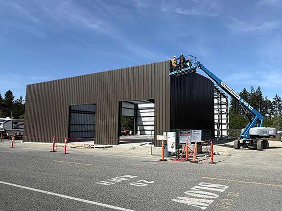 Construction team uses a life to add more exterior wall panels to PEMB structure