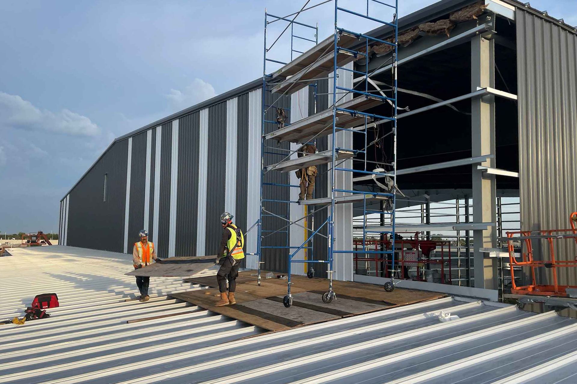 Tradespeople add metal panels to an industrial building in Winnipeg.