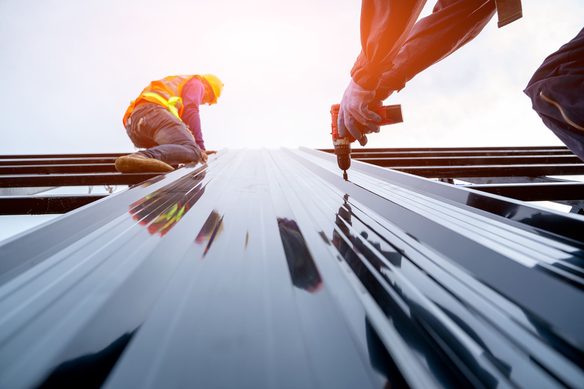 Workers install an exterior metal panel to a commercial building.