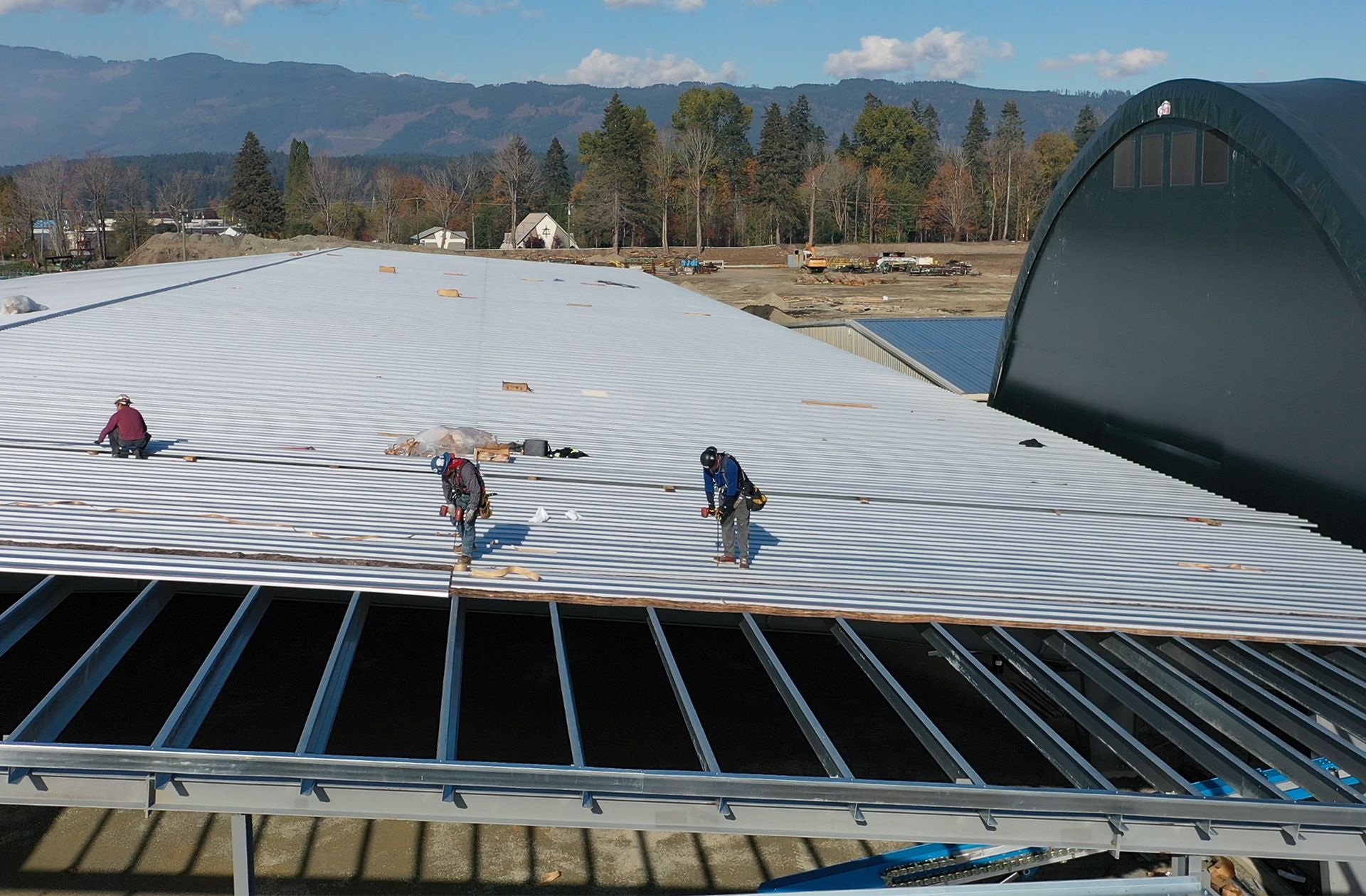 Skilled trades people add metal roofing to a lumber building in B.C.