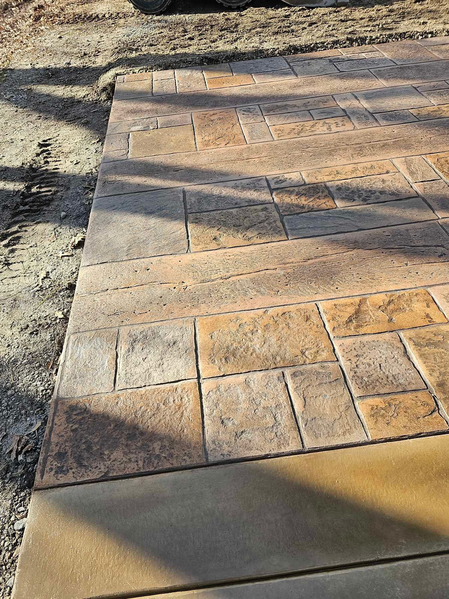 A concrete walkway with a brick pattern is being built.