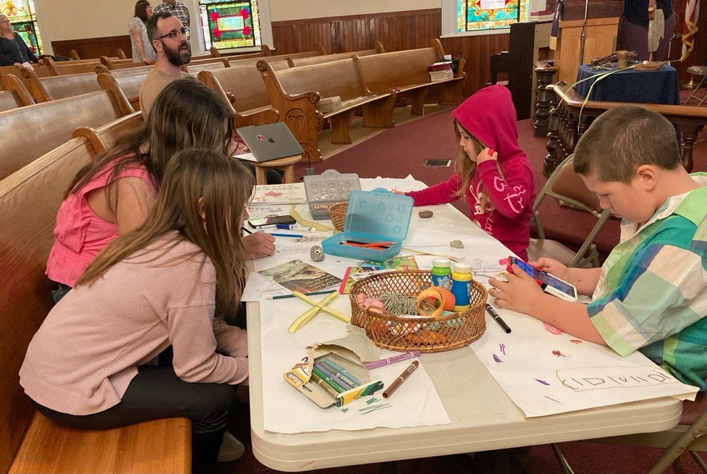 A group of children are sitting at a table in a church.