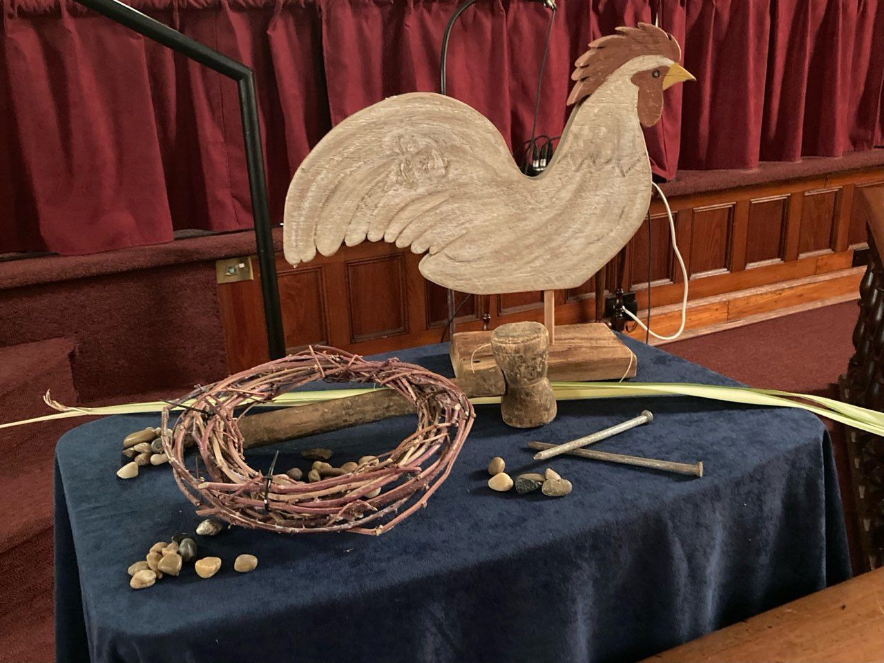 A table with a wooden rooster and a wreath on it