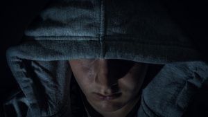 A close up of a person wearing a hoodie in the dark.