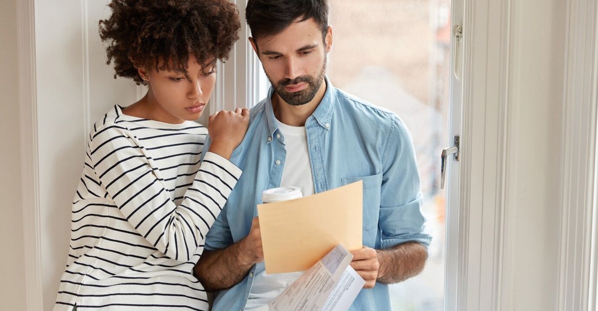 A man and a woman are standing next to each other looking at a piece of paper.