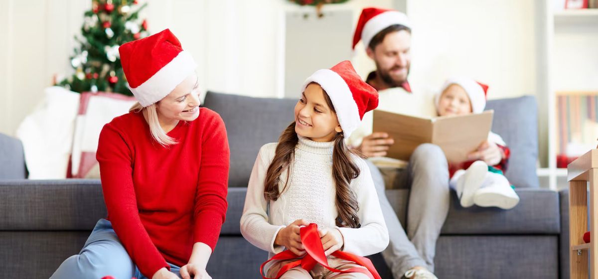 A family is sitting on a couch wearing santa hats.