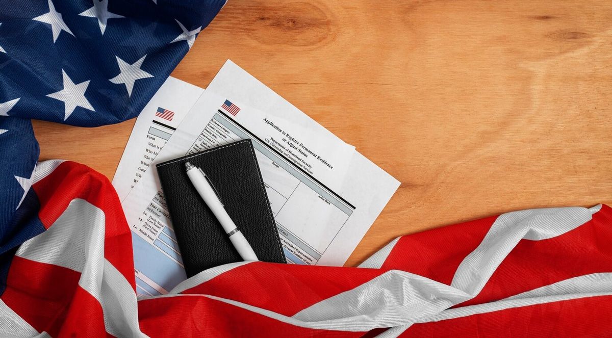 An american flag is laying on a wooden table with papers and a pen