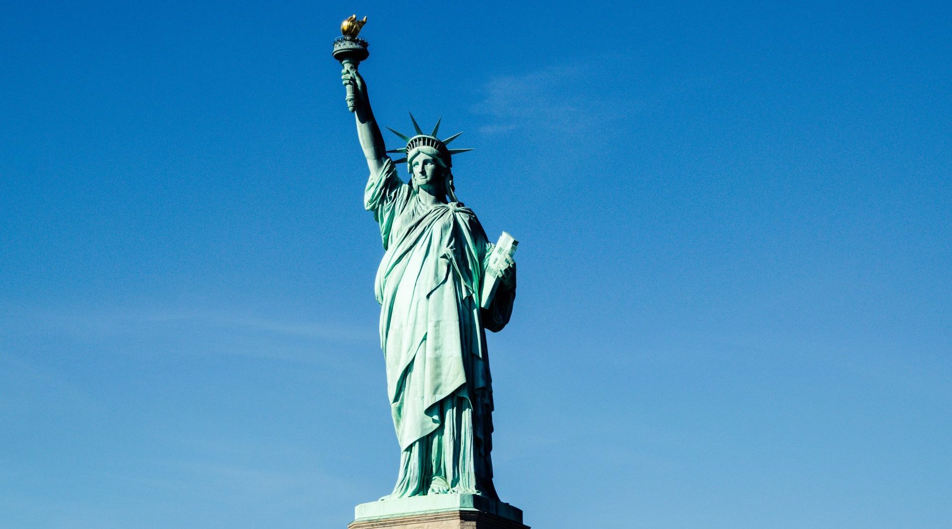 The statue of liberty is against a blue sky