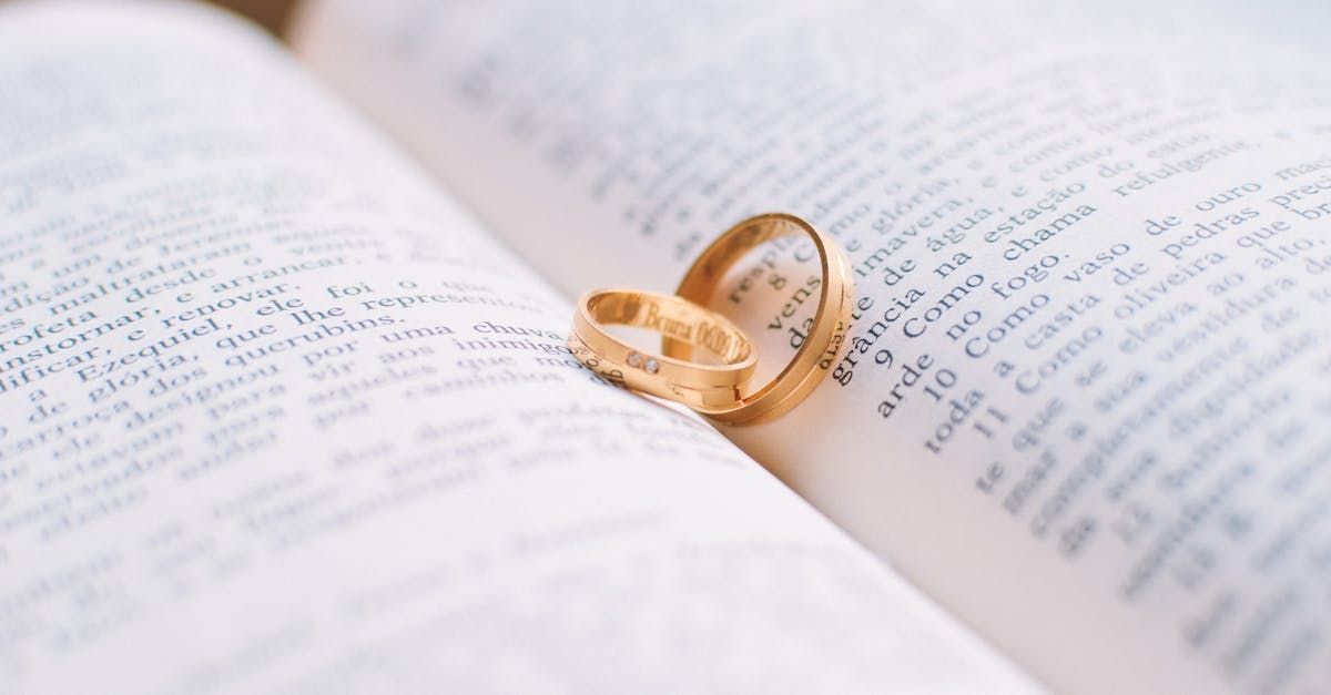Two wedding rings are sitting on top of an open book.