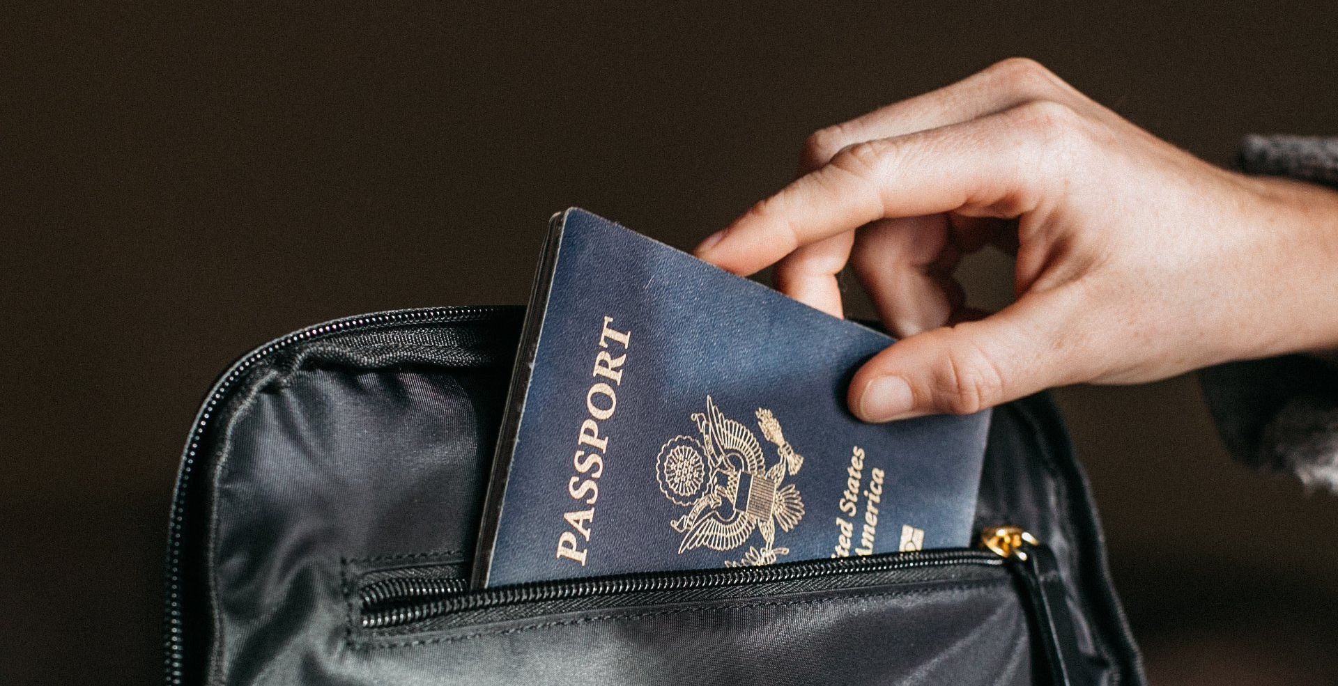 A person is taking a passport out of a black bag