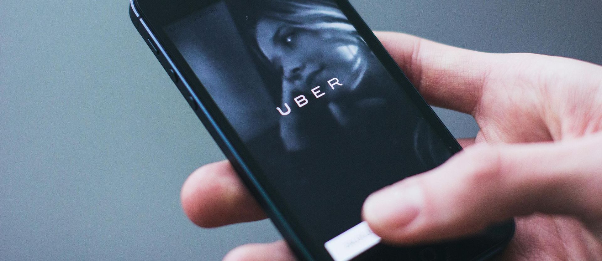 A person is holding a cell phone with the uber app on the screen.