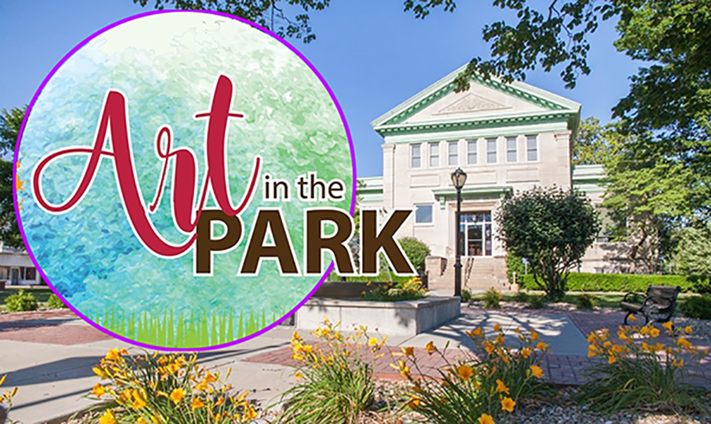 A logo for art in the park with a picture of a building in the background.