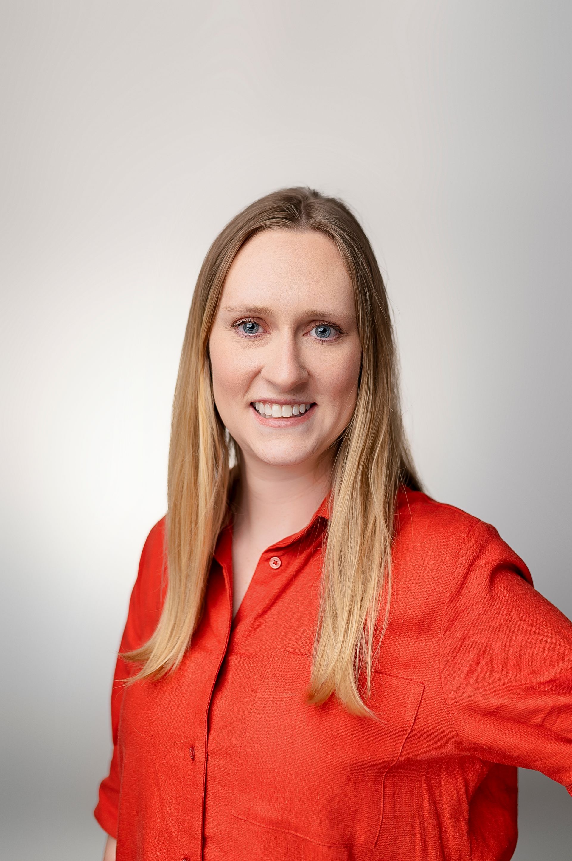 A woman in a red shirt is smiling for the camera.
