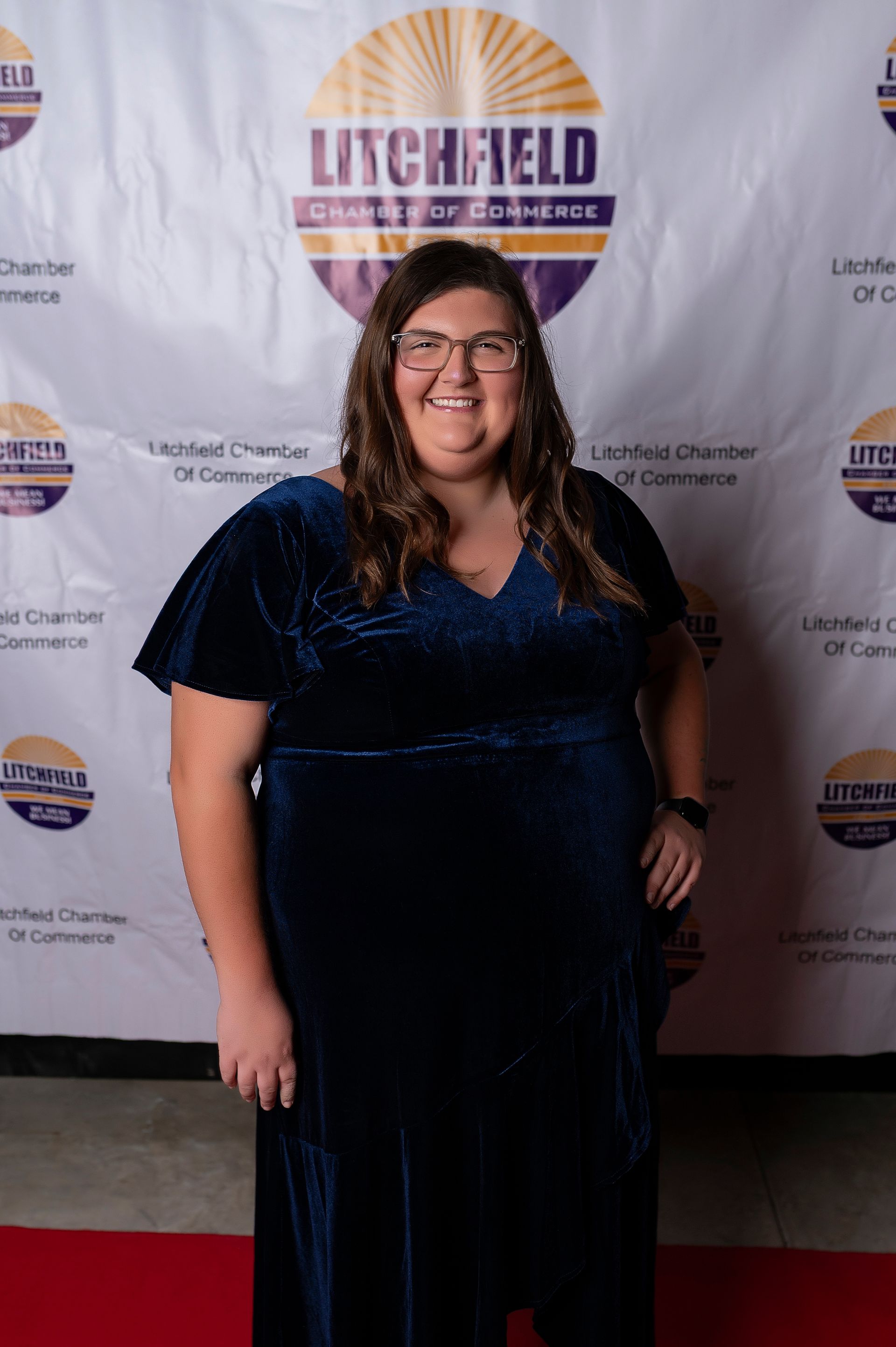 A woman in a blue dress is standing in front of a red carpet.