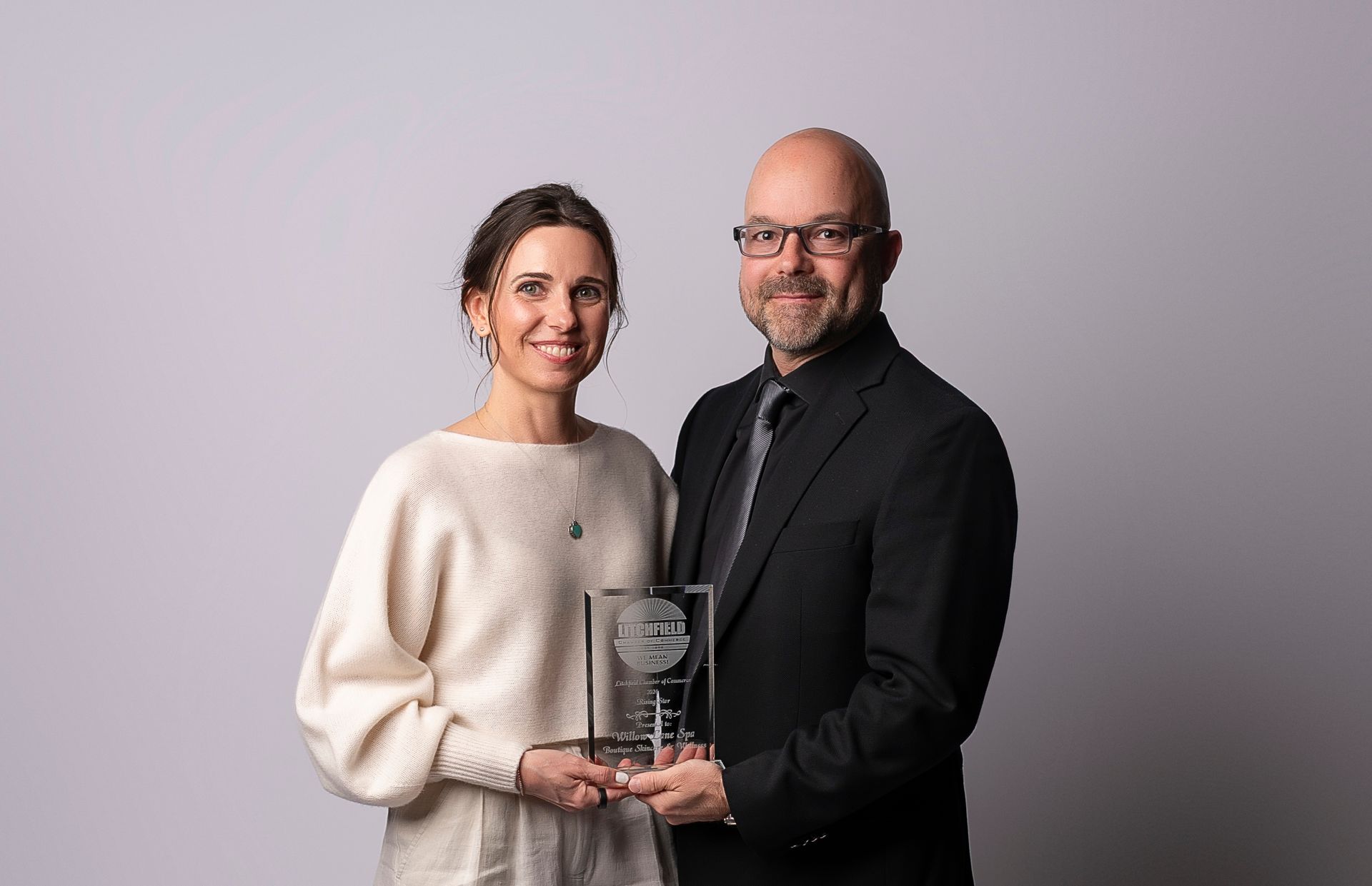 A man and a woman are standing next to each other holding an award.