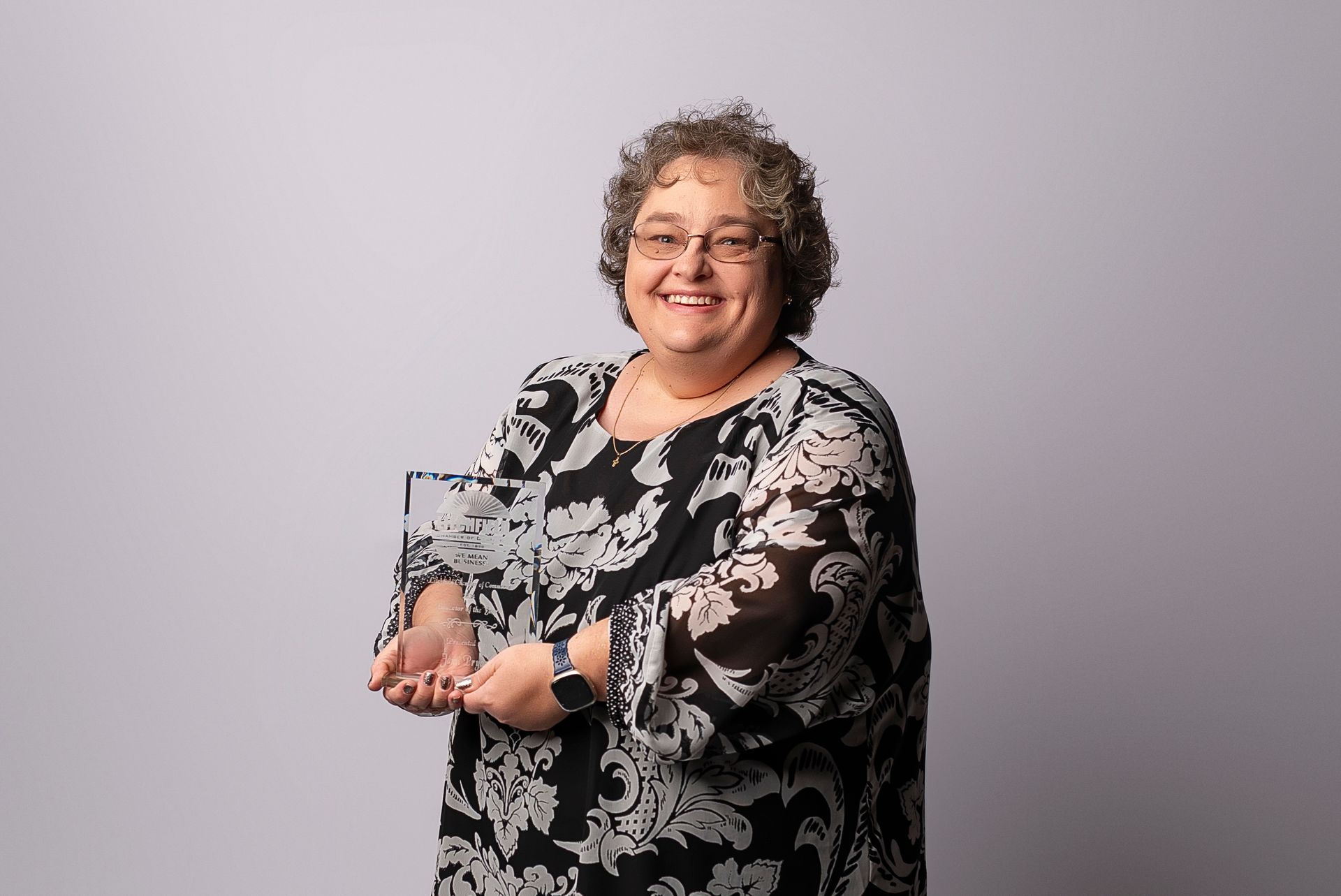 A woman in a black and white dress is holding a trophy in her hands.