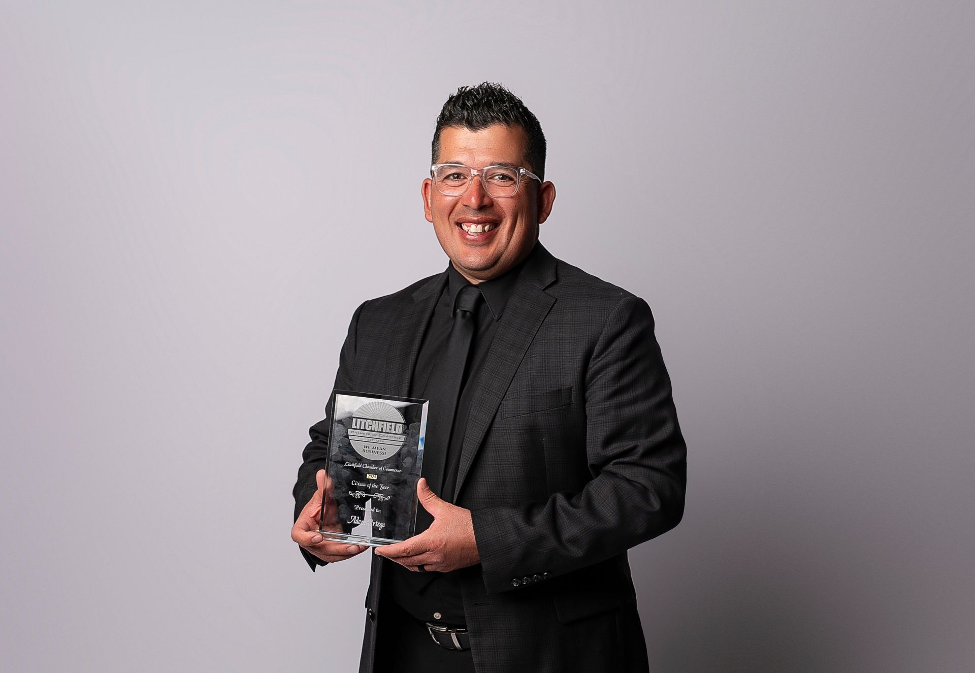 A man in a suit and tie is holding a trophy.