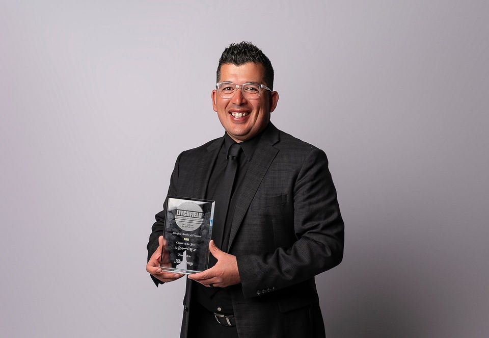 A man in a suit and tie is holding a trophy.