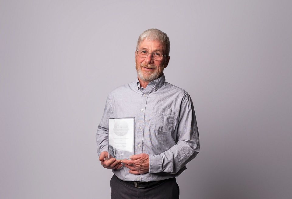 A man with a beard is holding a trophy in his hands.