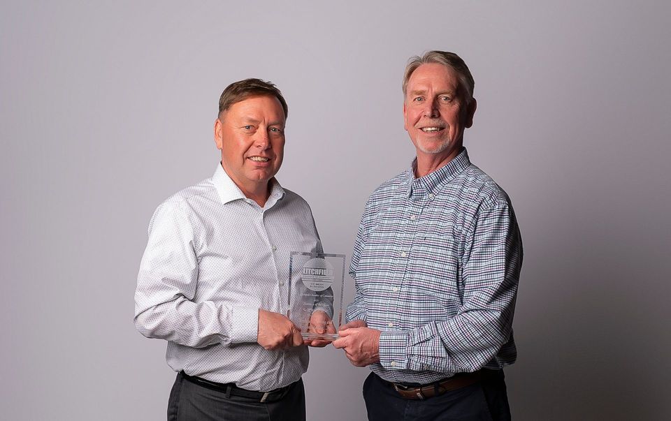 Two men are standing next to each other holding a trophy.