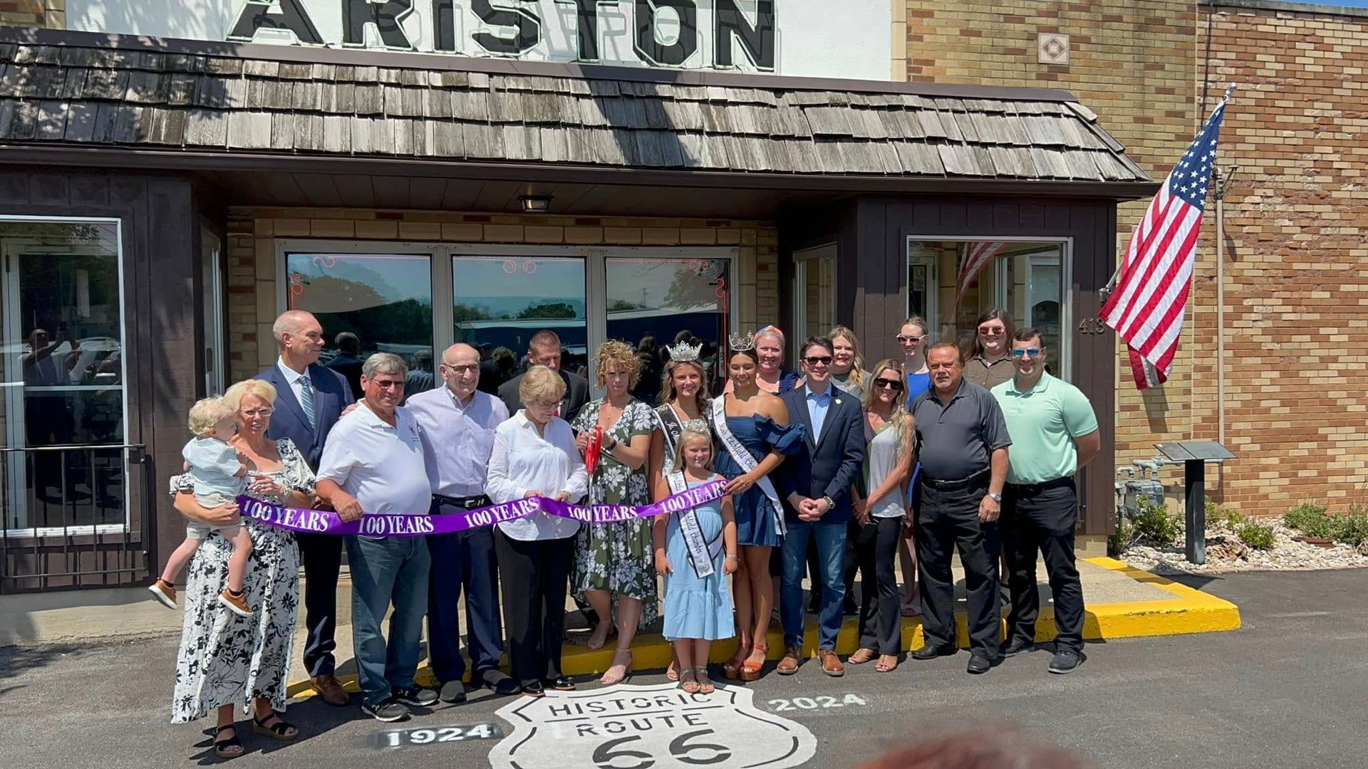 A group of people are standing in front of a building cutting a ribbon.