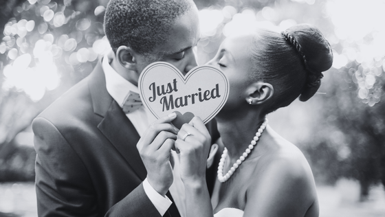 bride and groom holding up heart that says just married