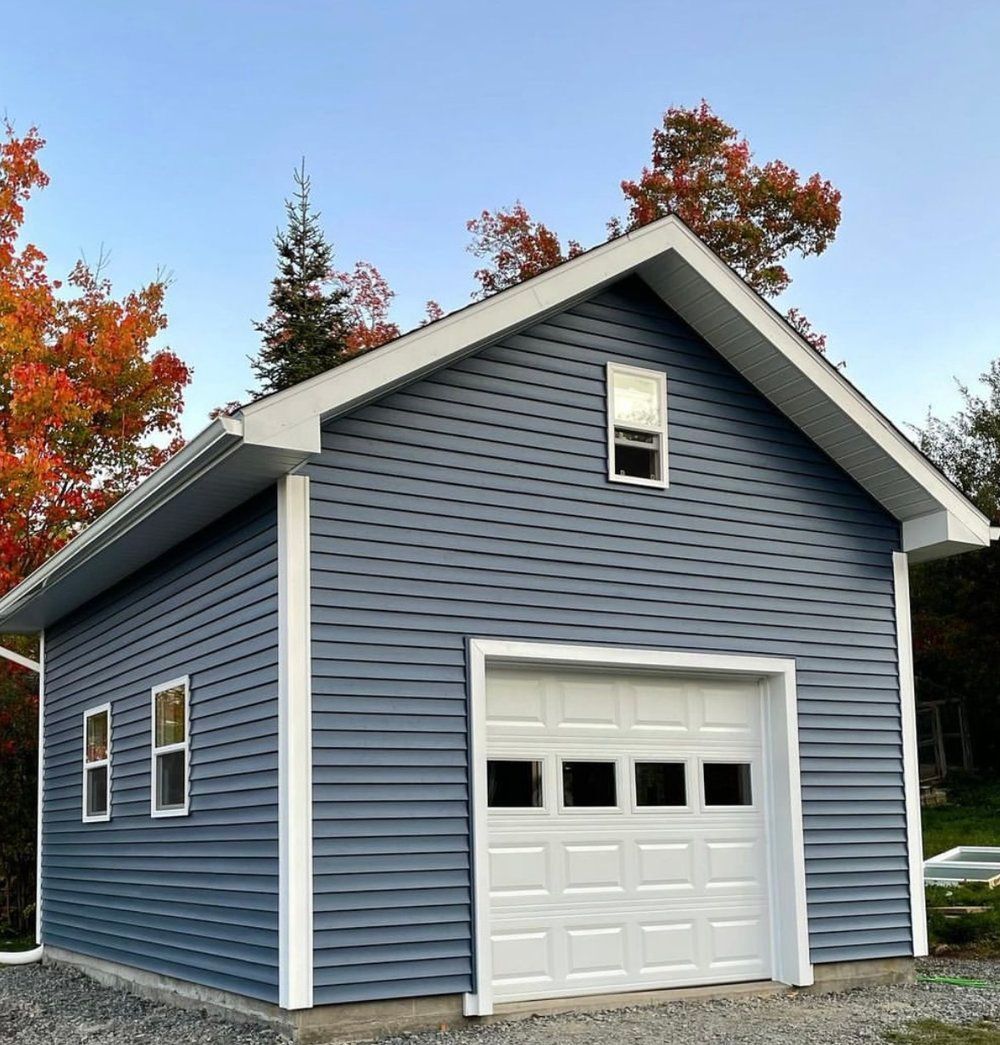 A blue garage with white trim and a white garage door