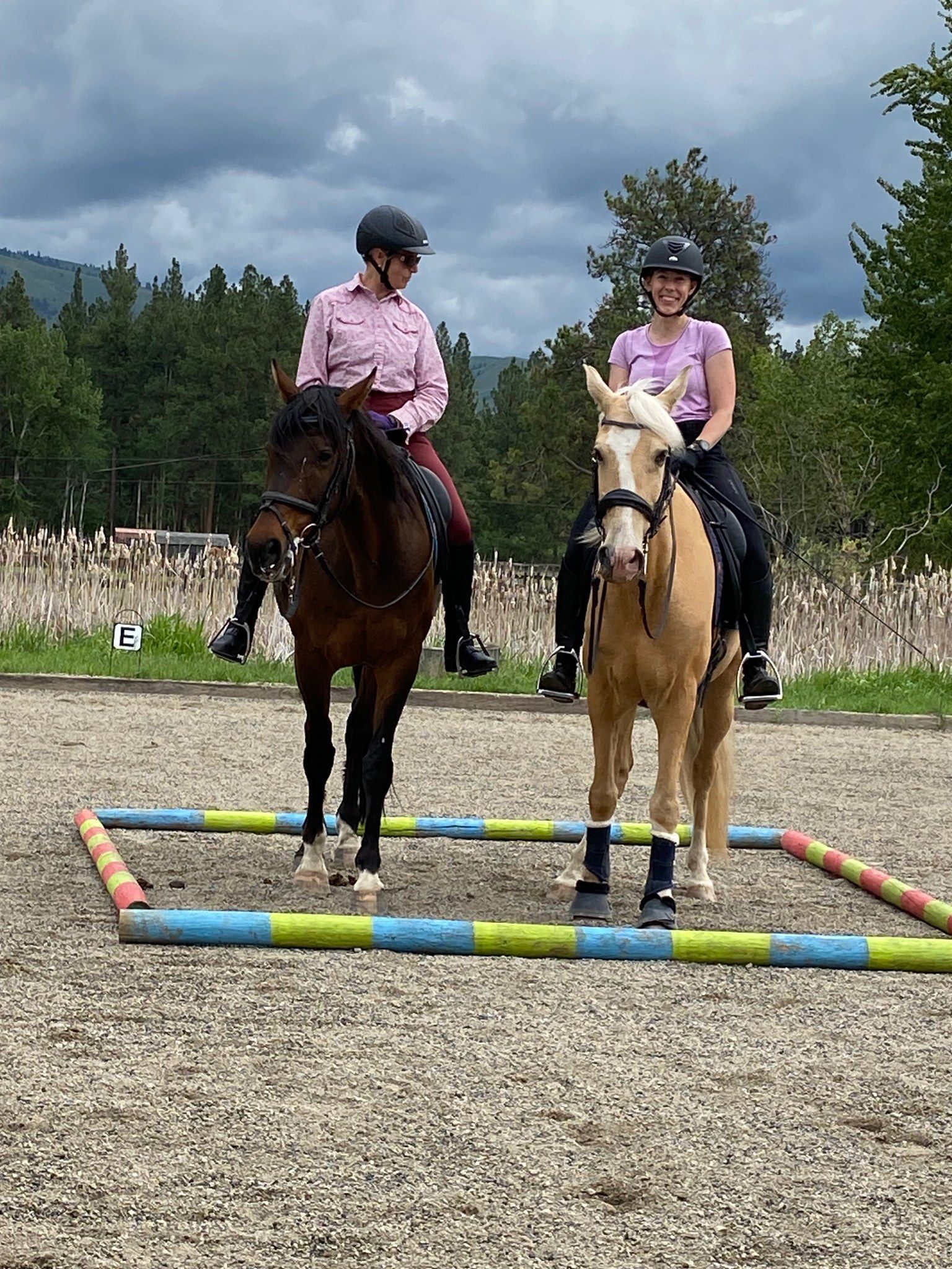 Two women are riding horses in a dirt field.