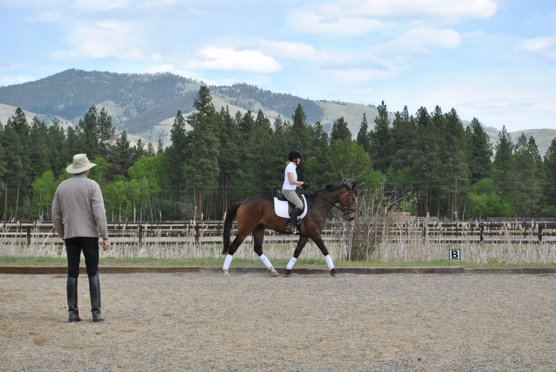 A man is standing next to a woman riding a horse.
