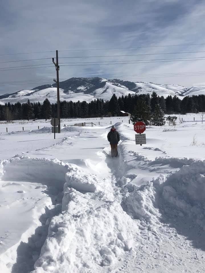 A man is standing in the snow near a stop sign.
