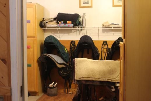 A room with saddle racks and a saddle on a bench.