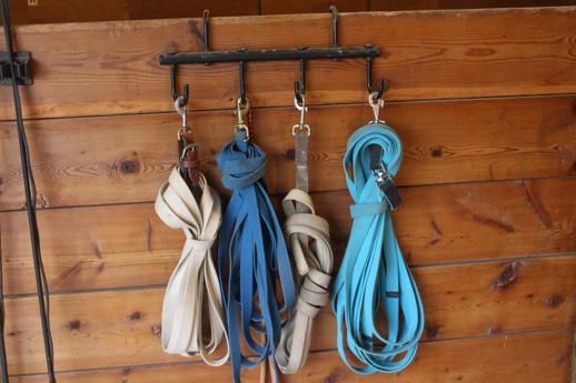Four ropes are hanging on hooks on a wooden wall.