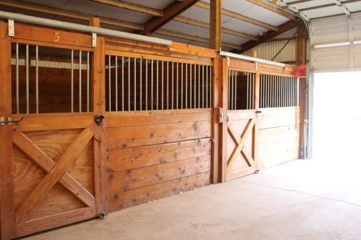 A row of wooden horse stables with sliding doors