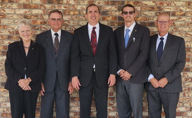 The front door of a house with a porch and plants in front of it.