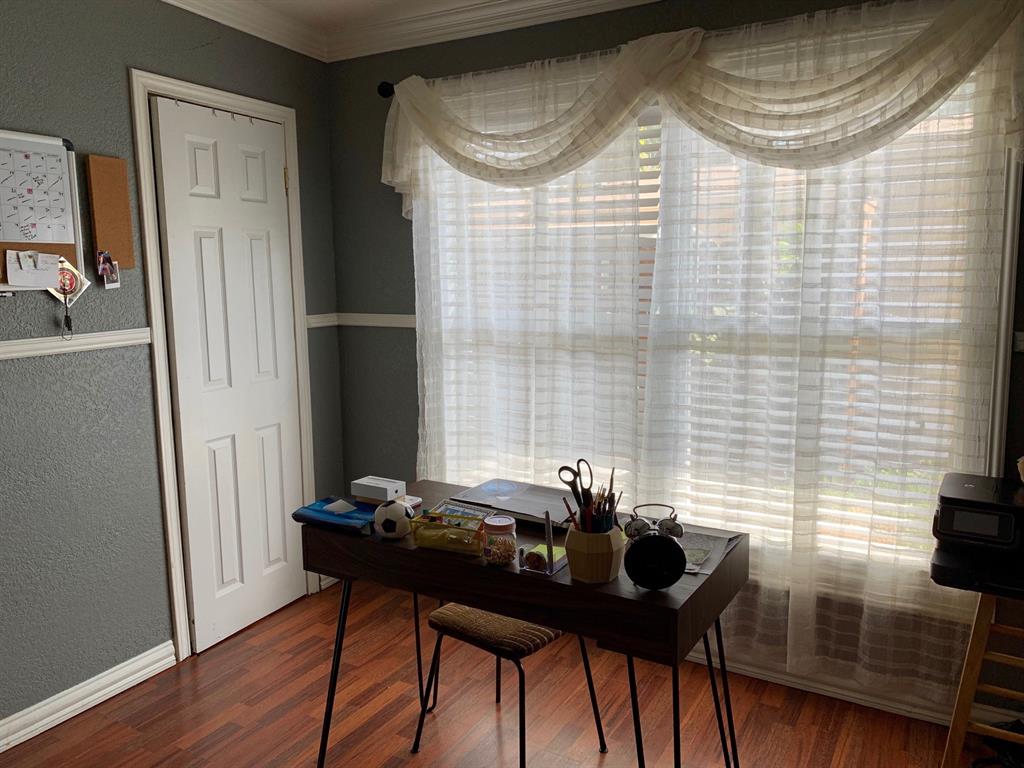 A room with a desk and a window with blinds.