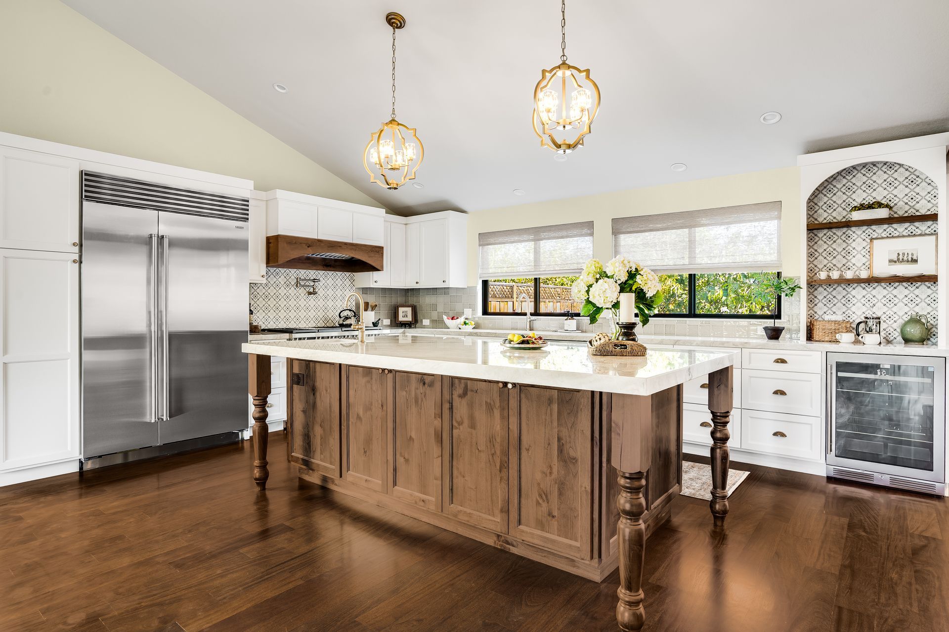 Spacious kitchen with a large island, white cabinets, stainless steel appliances, and hardwood floors.