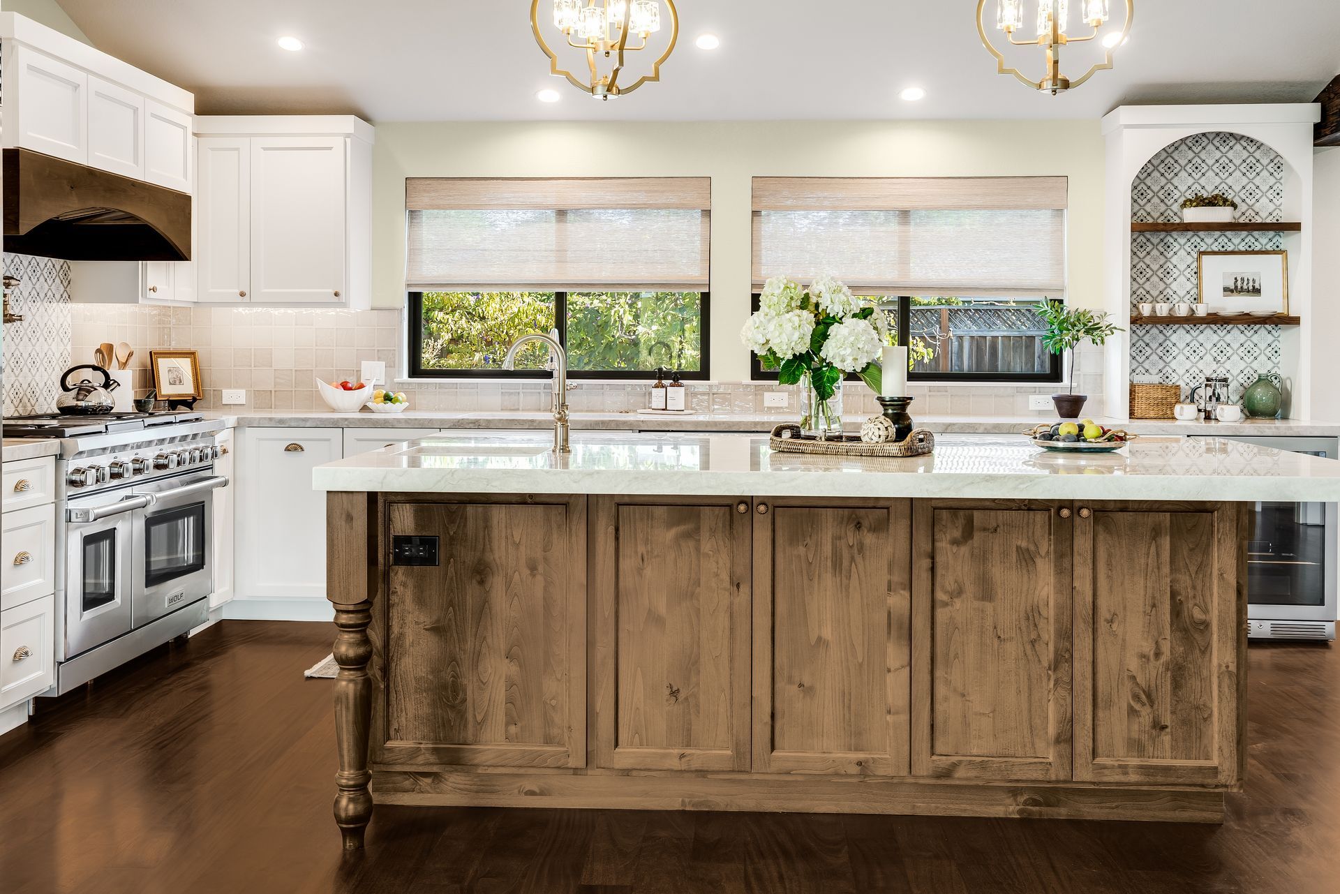 Kitchen with white cabinets, wooden island, stainless steel appliances, and large windows.