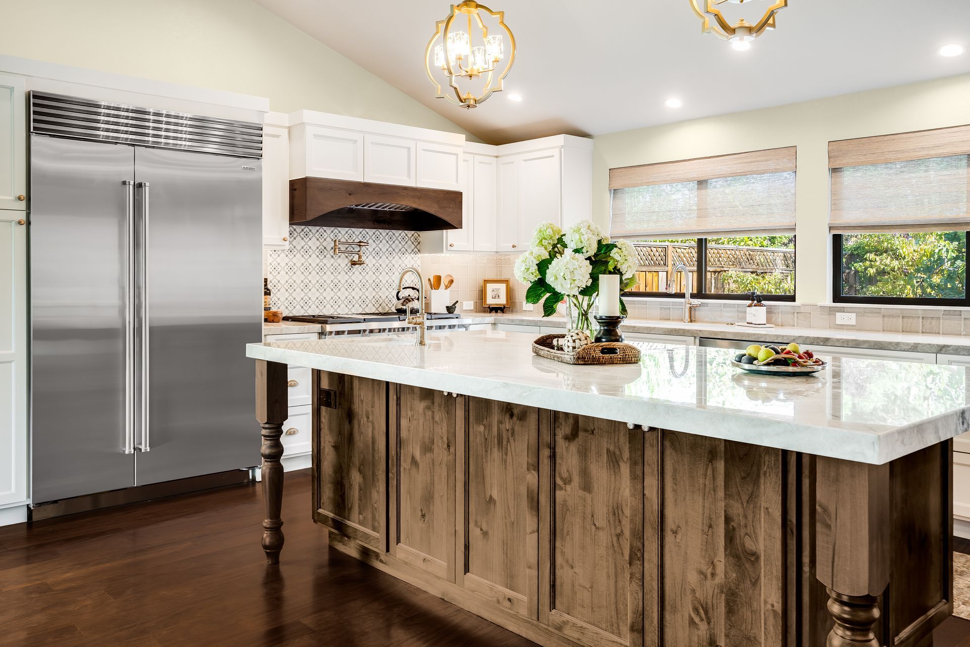 Spacious kitchen with a stainless steel refrigerator, white cabinets, and a wood-paneled island.