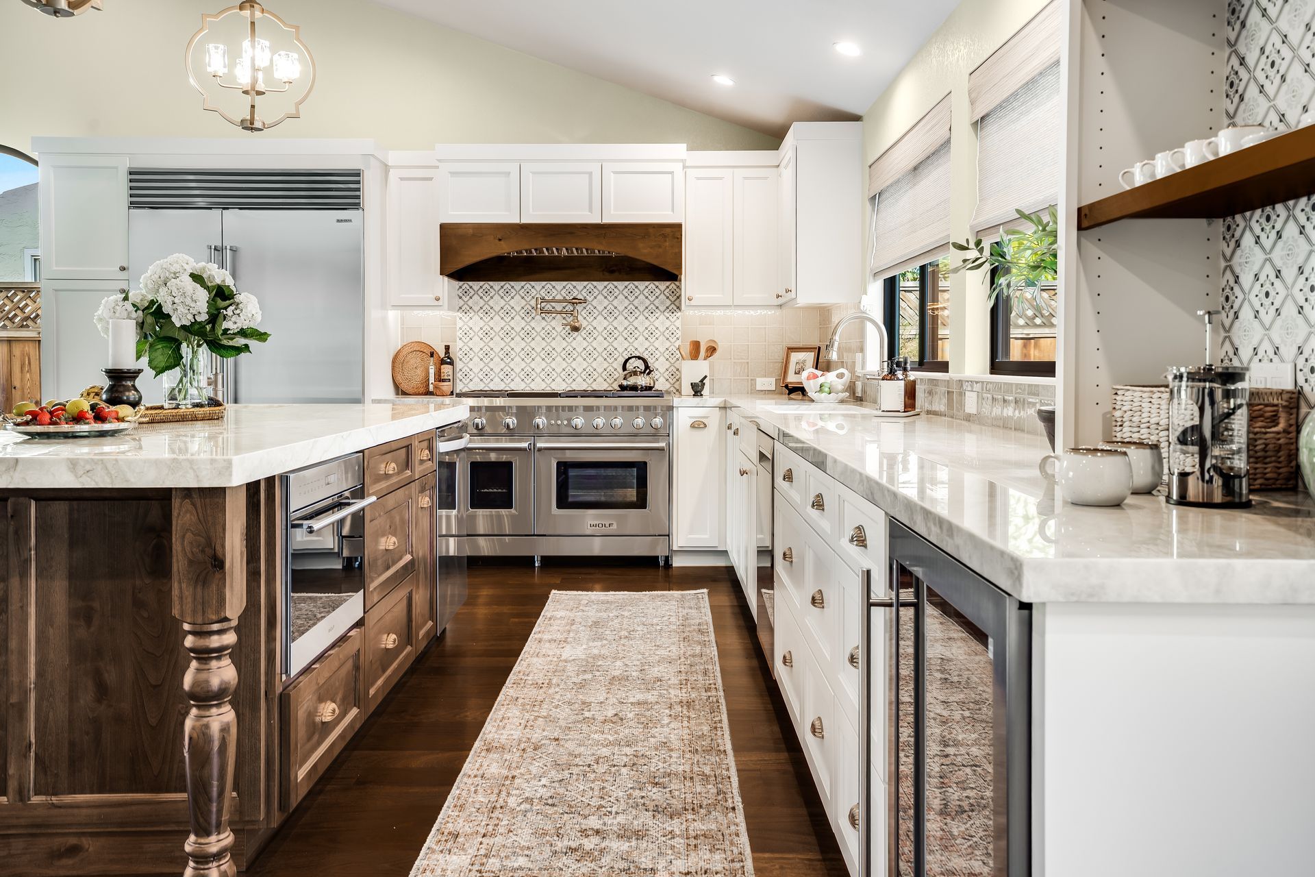 Modern kitchen with white and wood cabinets, stainless steel appliances, and a marble countertop.