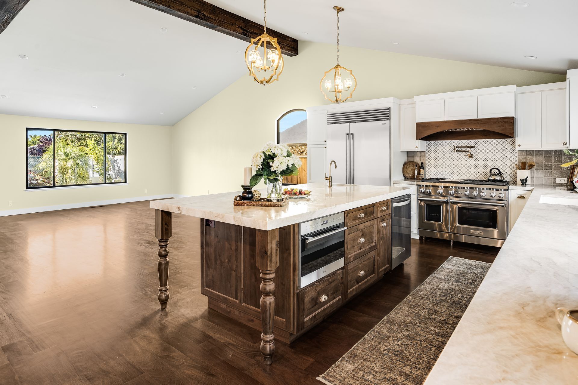 Spacious kitchen with large island, stainless steel appliances, wooden floors, and white cabinets.