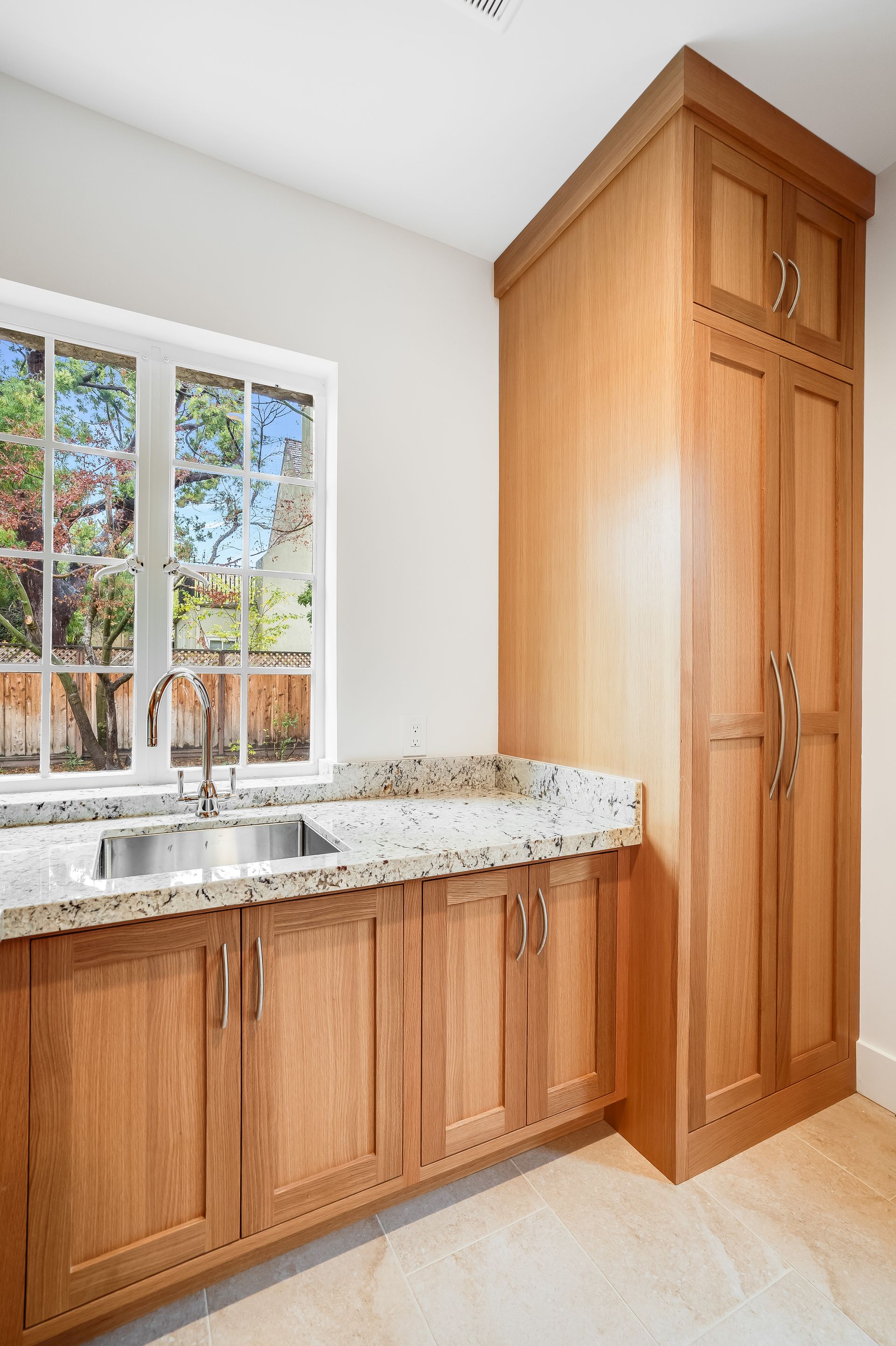 A kitchen with wooden cabinets , granite counter tops , a sink and a window.