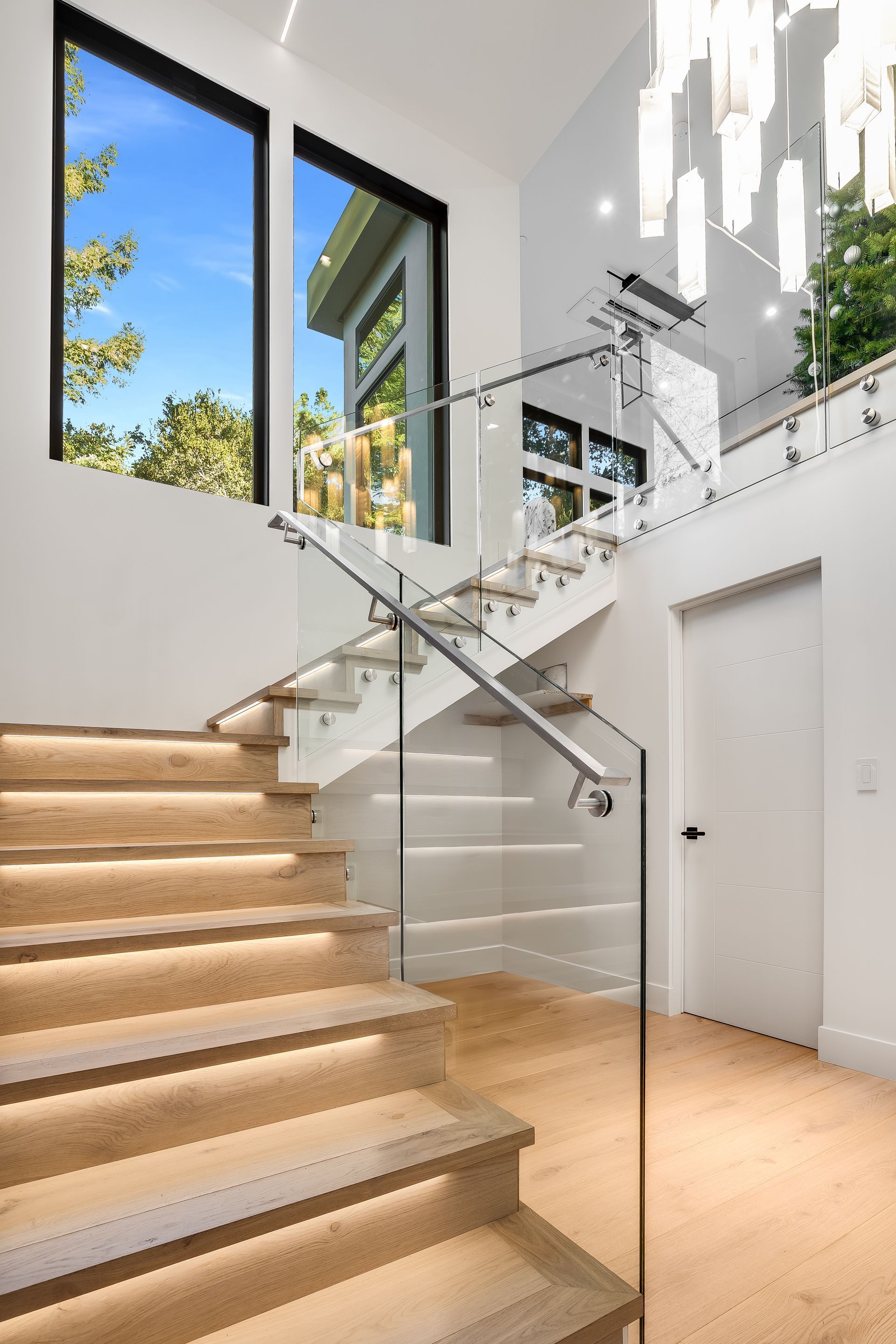 A modern staircase with wooden steps and a glass railing.