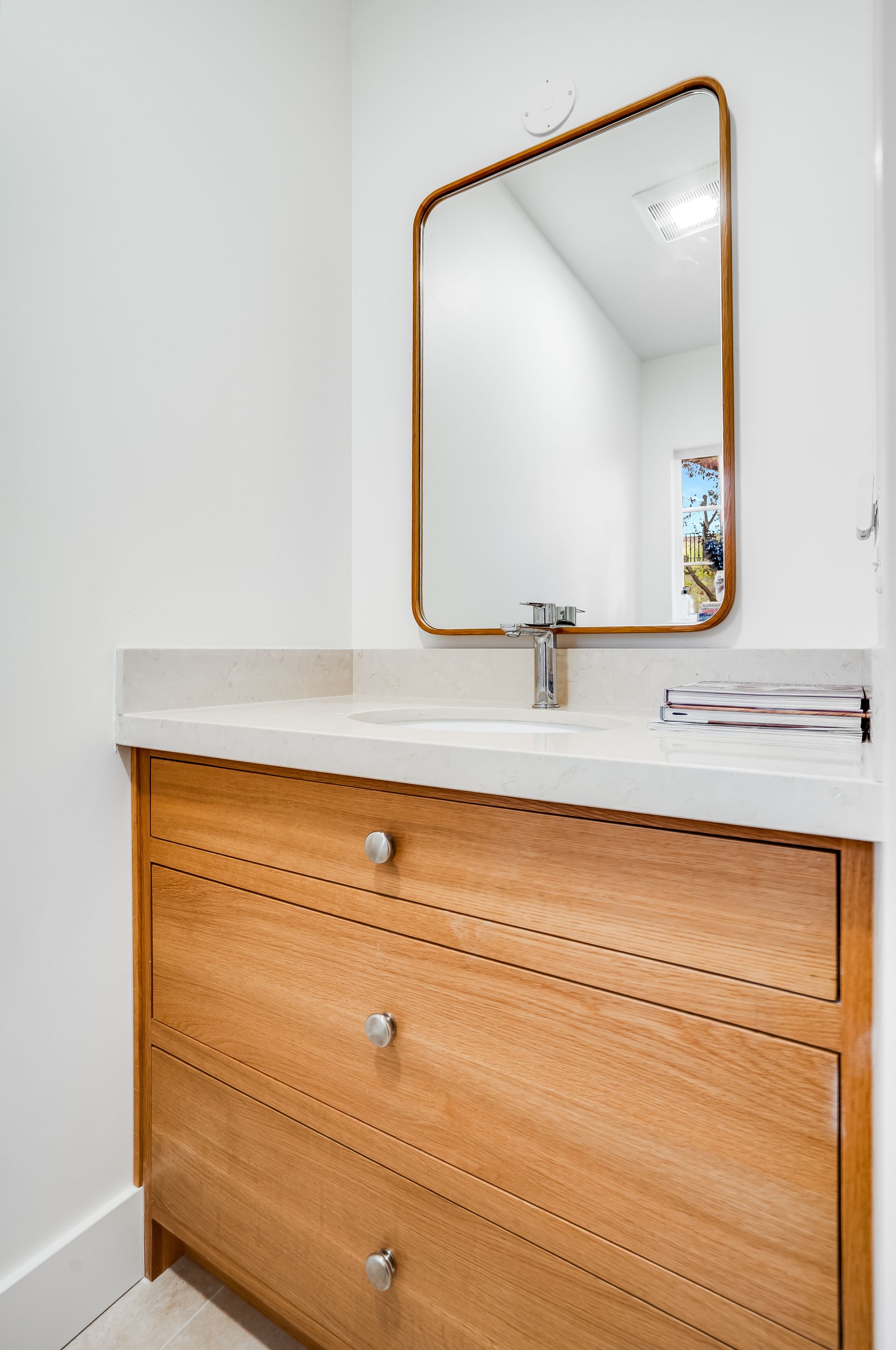 A bathroom with a wooden vanity and a mirror.