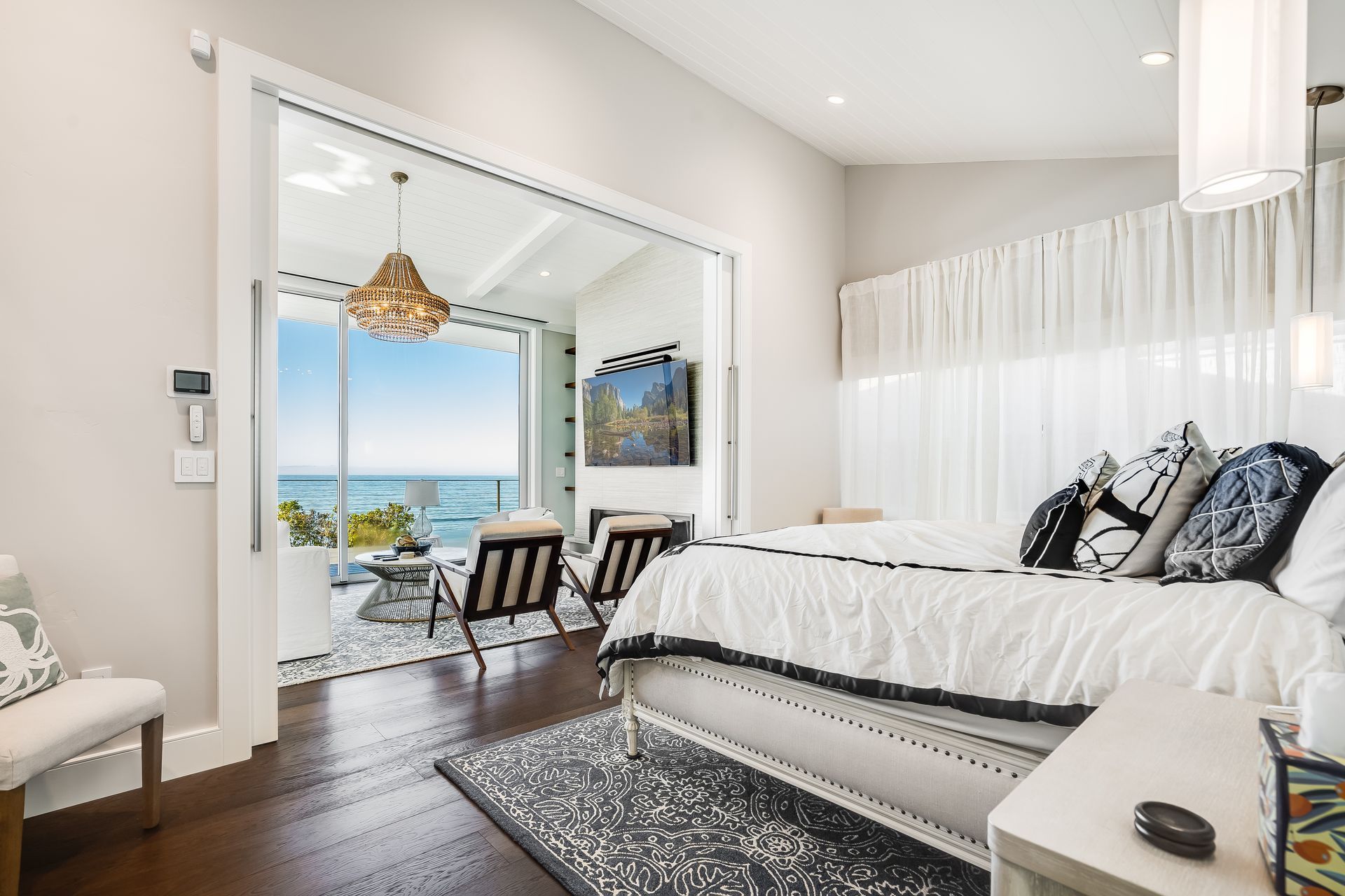 There is a large bed in the middle of the room with a view of the ocean.