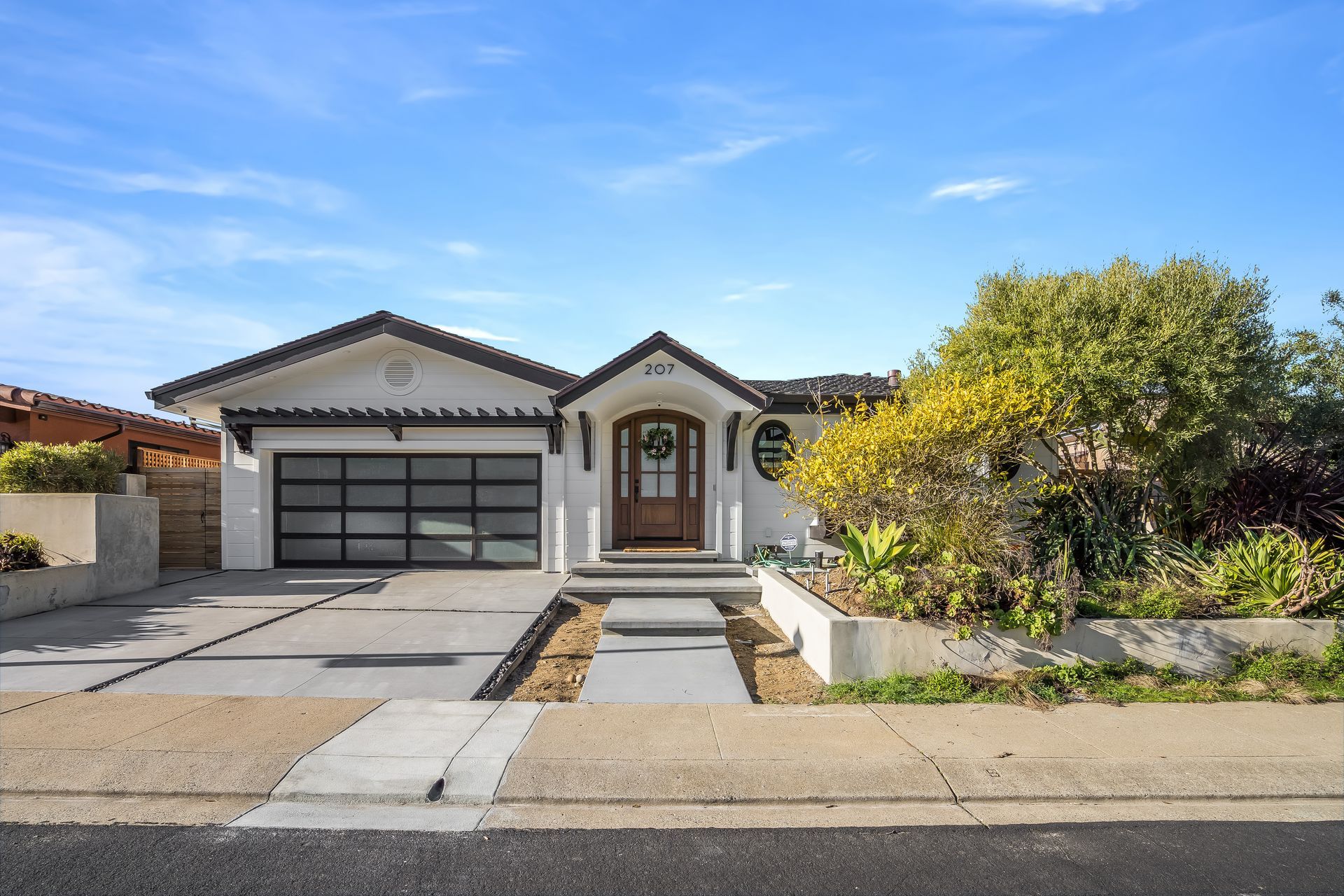 A white house with a black garage door is for sale