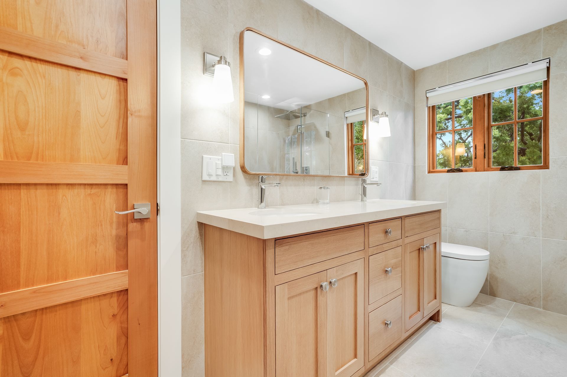 A bathroom with two sinks , a toilet , and a large mirror.