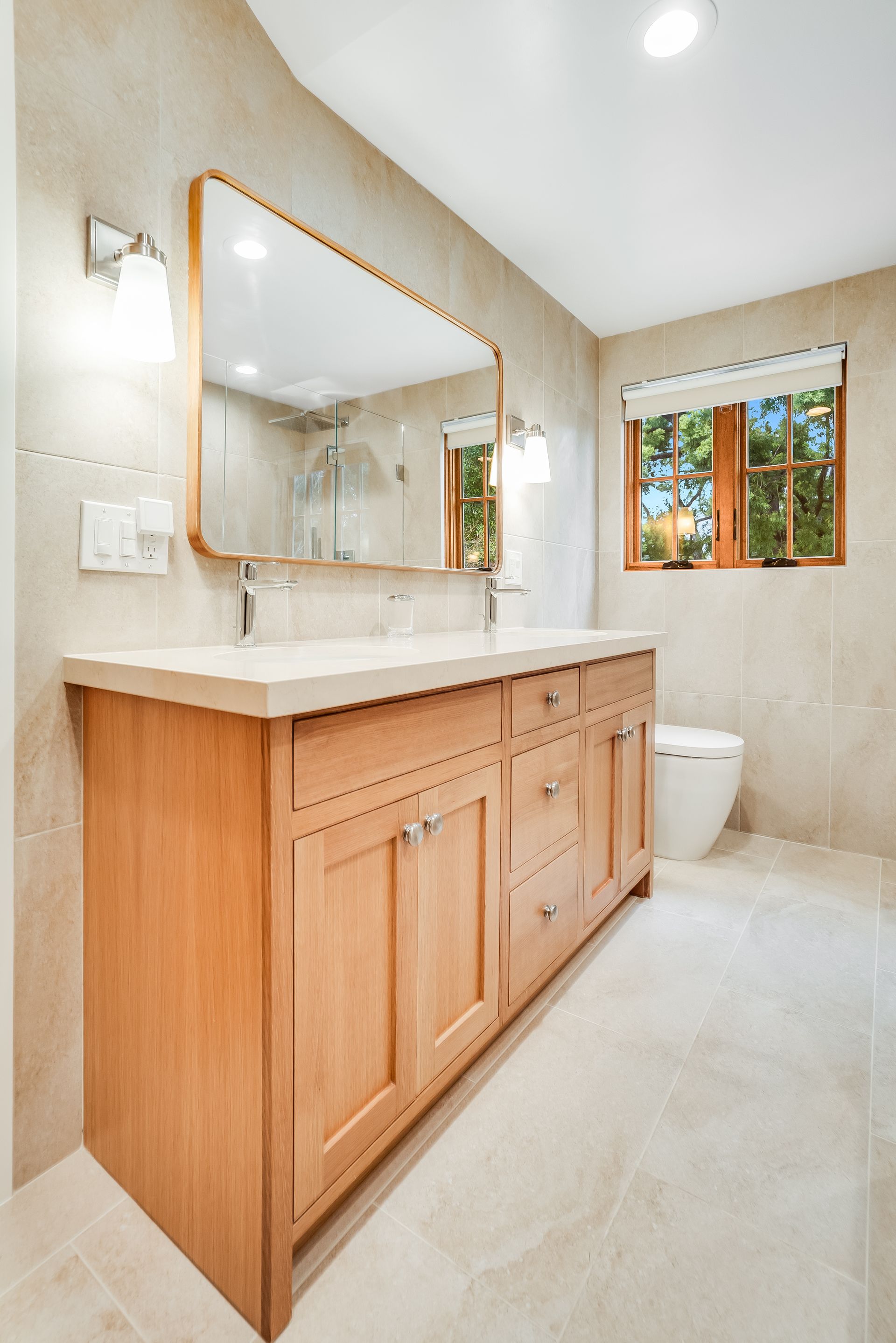 A bathroom with two sinks , a toilet , and a large mirror.